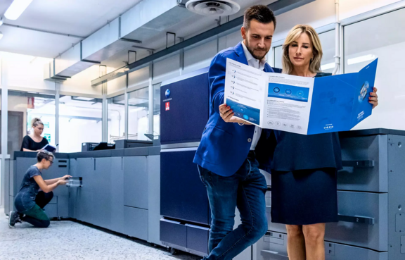Success story title image showing a print room with a Konica Minolta printer and print operators examining a job