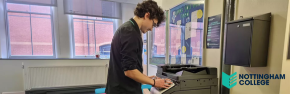 A photo of the Nottingham College print room with an operator using a Konica Minolta printer
